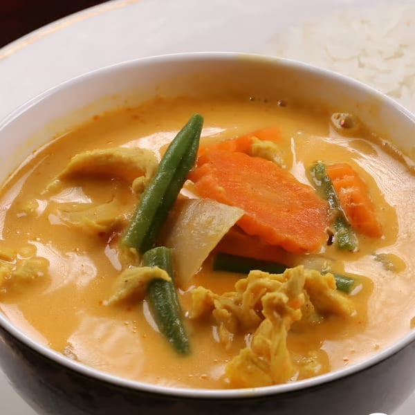 Cambodian red curry with chicken, green beans, carrots, and onions, served with rice.