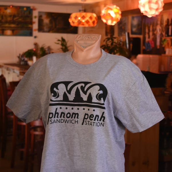 Gray Phnom Penh Sandwich Station t-shirt with black logo on a mannequin in a restaurant.